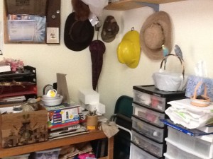 corner of the office showing clutter on top of small table and hats on wall