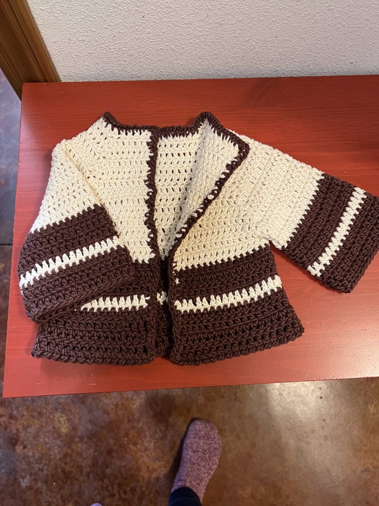 The baby sweater with one side bent back to show how the inside is just the same as the right side (the only difference is where I tied off yarns).